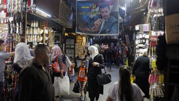 In this May 18, 2017 photo, Syrians shop under a banner showing President Bashar Assad at the Hamadiyah market, in the Old City of Damascus, Syria. In this May 18, 2017 photo, Syrians shop under a banner showing President Bashar Assad at the Hamadiyah market, in the Old City of Damascus, Syria. - Sputnik International