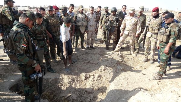 Iraqi forces search the site of a suspected mass grave containing the remains of victims of the Islamic State group, near the former al bakara military base on November 11, 2017, south west of Hawija - Sputnik International