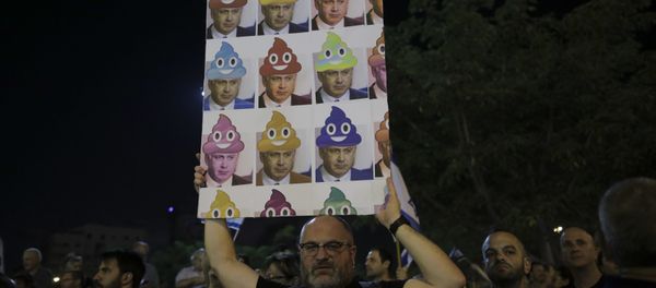 In this Saturday, Aug. 26, 2017 file photo, a man holds up a poster during a weekly protest against Israeli Prime Minister Benjamin Netanyahu, seen on the poster, in front of the home of Israel's attorney general Avichai Mandelblit, in Petah Tikva, Israel. With a slew of corruption scandals closing in on him, Netanyahu is increasingly dropping what remains of his statesmanlike persona in favor of nationalist rhetoric popular with his base. By cozying up to conservatives, anti-migrant voices and West Bank settlers, Netanyahu appears to be trying to reframe the corruption allegations as an ideological witch-hunt. - Sputnik International