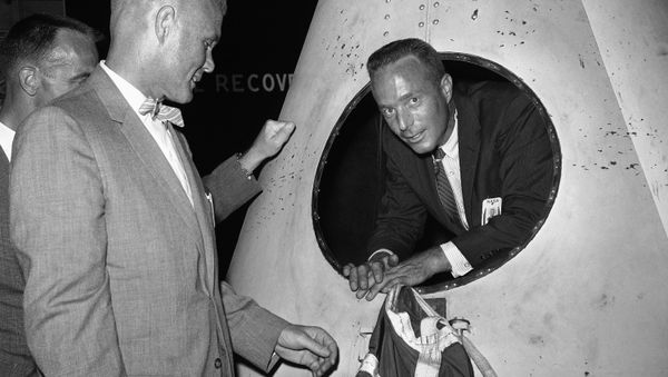 Navy Lt. Scott Carpenter, one of seven astronauts training for space flight, looks out an opening in a rocket nose cone model during tour of Langley Research Center, Virginia, July 8, 1959, by newsmen Marine Lt. Col. John Glenn, another space trainee, is at left. - Sputnik International