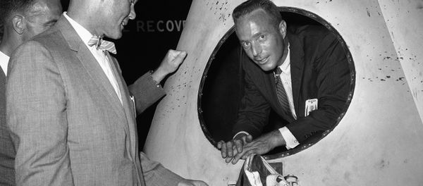 Navy Lt. Scott Carpenter, one of seven astronauts training for space flight, looks out an opening in a rocket nose cone model during tour of Langley Research Center, Virginia, July 8, 1959, by newsmen Marine Lt. Col. John Glenn, another space trainee, is at left. - Sputnik International