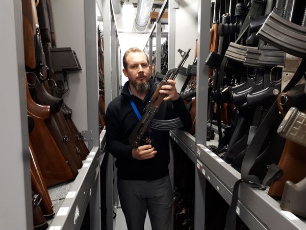 A member of the forensic firearms unit shows off one of the 7,500 guns they have stored - Sputnik International