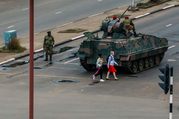 Young women walk past an armoured personnel carrier that stations by an intersection as Zimbabwean soldiers regulate traffic in Harare on November 15, 2017 - Sputnik International