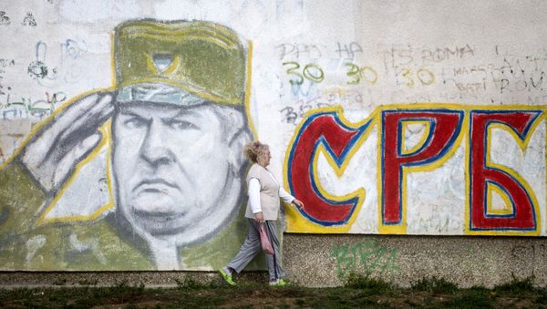 A woman walks past a graffiti depicting former Bosnian Serb commander Ratko Mladic and reading Serbia written in Cyrillic, painted on a wall in Belgrade on Nocember 22, 2017. - Sputnik International