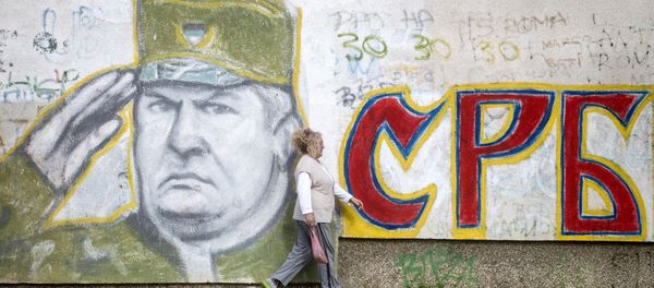A woman walks past a graffiti depicting former Bosnian Serb commander Ratko Mladic and reading Serbia written in Cyrillic, painted on a wall in Belgrade on Nocember 22, 2017. - Sputnik International