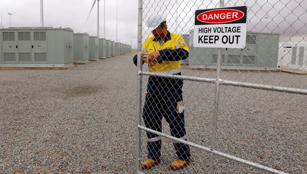 A worker checks the main gate for the compound housing the Hornsdale Power Reserve, featuring the world's largest lithium ion battery made by Tesla, during the official launch near the South Australian town of Jamestown, in Australia, December 1, 2017 - Sputnik International