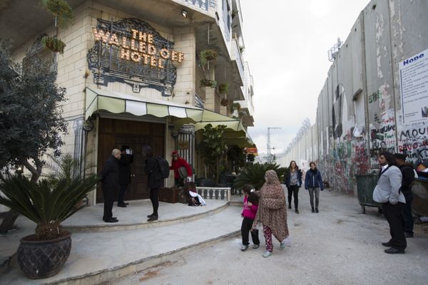 People pass by the The Walled Off Hotel and the Israeli security barrier in the West Bank city of Bethlehem People pass by the The Walled Off Hotel and the Israeli security barrier in the West Bank city of Bethlehem - Sputnik International