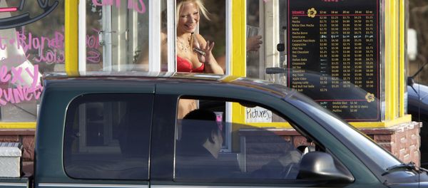 In this Feb. 2, 2010, file photo, a barista at a Grab-N-Go Bikini Hut espresso stand holds money as she waves to a customer, just outside the city limits of Everett, Wash., in Snohomish County. Seven bikini baristas and the owner of a chain of the coffee stands called Hillbilly Hotties sued the city of Everett, Washington, on Monday, Sept. 11, 2017, saying two recently passed ordinances banning bare skin violate their right to free expression. - Sputnik International
