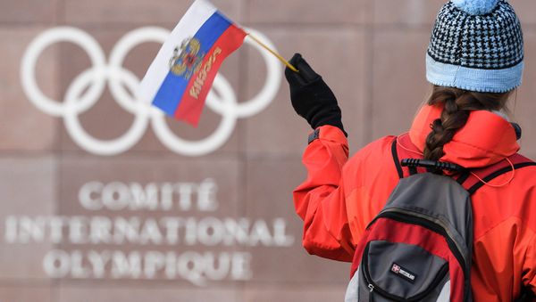 A supporter waves a Russian flag in front of the logo of the International Olympic Committee (IOC) at their headquarters on December 5, 2017 in Pully near Lausanne - Sputnik International