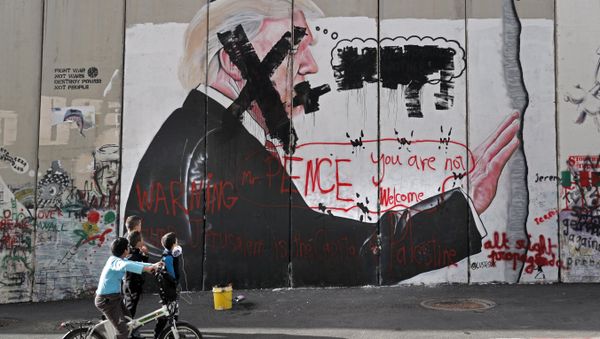 Palestinian children look at vandalised graffiti depicting US President Donald Trump and slogans against US Vice President Mike Pence painted on Israel's controversial separation barrier in the West Bank city of Bethlehem during clashes with Palestinian protestors near an Israeli checkpoint on December 7, 2017 - Sputnik International