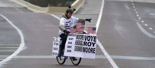 A man rides his bike with signs of support for Alabama Republican senatorial candidate Roy Moore around a venue that will host U.S. President Donald Trump later in the day in Pensacola, Florida, U.S., December 8, 2017 - Sputnik International