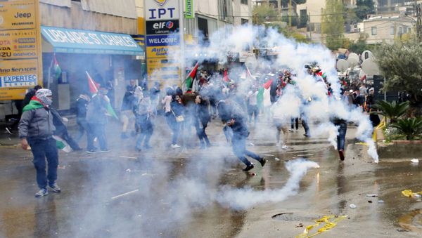 Protesters take cover from tear gas fired by riot police during a demonstration in front of the U.S. embassy in Aukar, east of Beirut, Lebanon, Sunday, Dec. 10, 2017 - Sputnik International