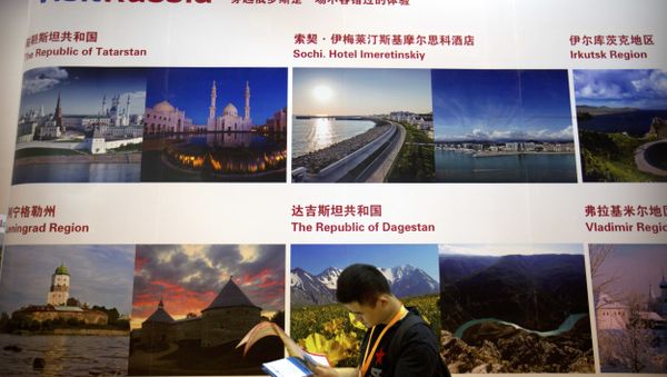 A man looks at a map as he walks past a signboard advertising tourist destinations in Russia at the Beijing International Tourism Expo in Beijing - Sputnik International