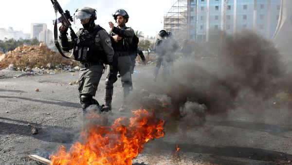 Israeli police officers walk in front of a burned barricade during a protest against U.S. President Donald Trump's decision to recognize Jerusalem as the capital of Israel, near the Jewish settlement of Beit El, near the West Bank city of Ramallah December 11, 2017 - Sputnik International