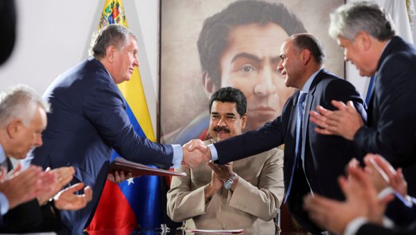 Head of Russian state oil firm Rosneft Igor Sechin (standing L) shakes hands with Venezuela's Oil Minister and President of the Venezuelan state oil company PDVSA Manuel Quevedo, in front of Venezuela's President Nicolas Maduro, in Maiquetia, Venezuela December 16, 2017. - Sputnik International