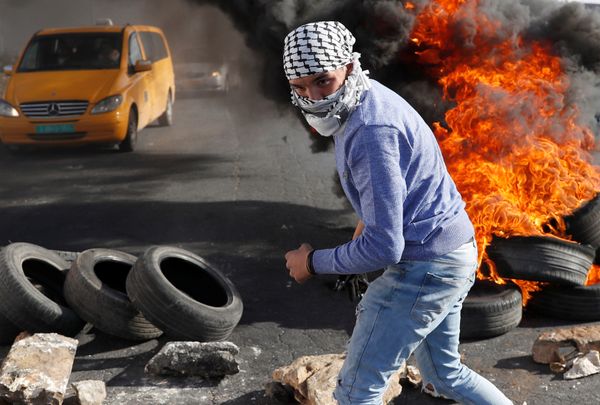 A Palestinian protester walks in front of a burned barricade during a protest against U.S. President Donald Trump's decision to recognize Jerusalem as the capital of Israel, near the Jewish settlement of Beit El, near the West Bank city of Ramallah December 14, 2017 A Palestinian protester walks in front of a burned barricade during a protest against U.S. President Donald Trump's decision to recognize Jerusalem as the capital of Israel, near the Jewish settlement of Beit El, near the West Bank city of Ramallah December 14, 2017 - Sputnik International