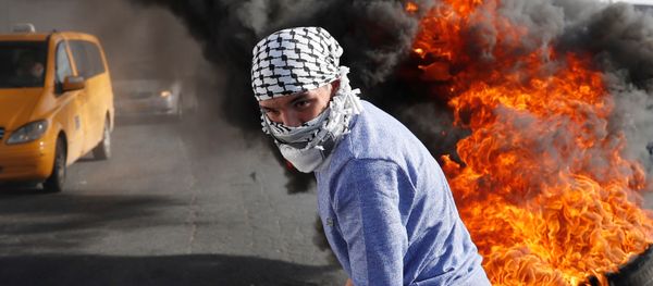 A Palestinian protester walks in front of a burned barricade during a protest against U.S. President Donald Trump's decision to recognize Jerusalem as the capital of Israel, near the Jewish settlement of Beit El, near the West Bank city of Ramallah December 14, 2017 A Palestinian protester walks in front of a burned barricade during a protest against U.S. President Donald Trump's decision to recognize Jerusalem as the capital of Israel, near the Jewish settlement of Beit El, near the West Bank city of Ramallah December 14, 2017 - Sputnik International