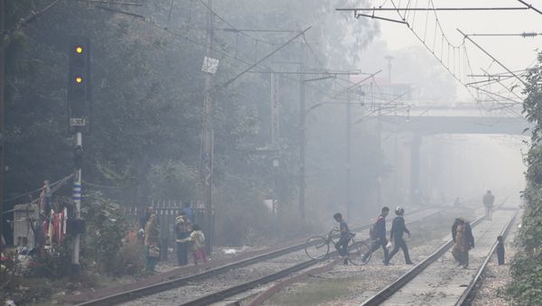 Indian residents walk amid heavy smog near the Lodhi railway station in New Delhi - Sputnik International