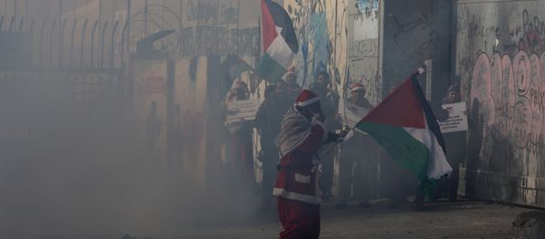 A Palestinian dressed as Santa Claus reacts from tear gas fired by Israeli troops during clashes in the West Bank city of Bethlehem, December 23, 2017 A Palestinian dressed as Santa Claus reacts from tear gas fired by Israeli troops during clashes in the West Bank city of Bethlehem, December 23, 2017 - Sputnik International