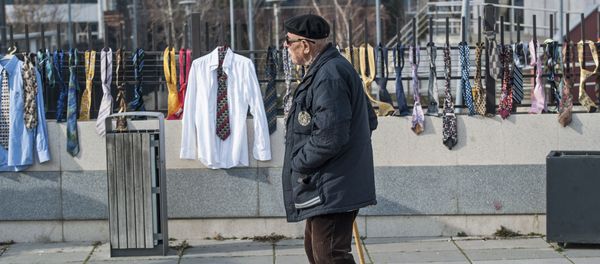 A man passes by hundreds of collected ties and shirts hanging on the fence of the government building on Tuesday, Dec. 26, 2017, in Kosovo capital Pristina - Sputnik International