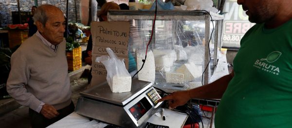 A vendor weighs cheese for a customer at a street market in Caracas, Venezuela December 19, 2017. Picture taken December 19, 2017. - Sputnik International