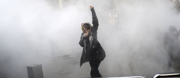 FILE - In this Saturday, Dec. 30, 2017 file photo taken by an individual not employed by the Associated Press and obtained by the AP outside Iran, a university student attends a protest inside Tehran University while a smoke grenade is thrown by anti-riot Iranian police, in Tehran, Iran - Sputnik International