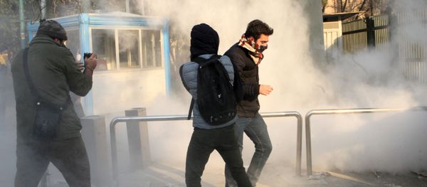 Iranian students run for cover from tear gas at the University of Tehran during a demonstration driven by anger over economic problems, in the capital Tehran on December 30, 2017 - Sputnik International