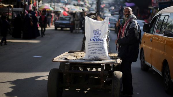 A Palestinian man stands next to a cart carrying a flour sack distributed by the United Nations Relief and Works Agency (UNRWA) in Khan Younis refugee camp in the southern Gaza Strip January 3, 2018 - Sputnik International