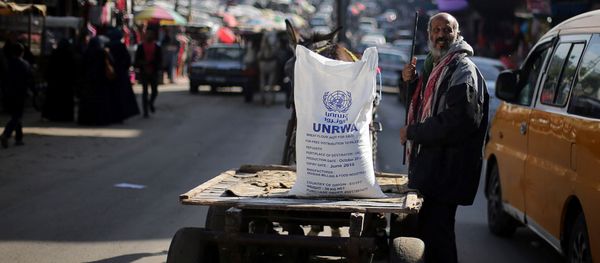 A Palestinian man stands next to a cart carrying a flour sack distributed by the United Nations Relief and Works Agency (UNRWA) in Khan Younis refugee camp in the southern Gaza Strip January 3, 2018 - Sputnik International