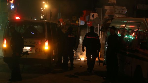 Police vehicles stop in front of burning tires set up by protesters during demonstrations against rising prices and tax increases, in Tunis, Tunisia - Sputnik International