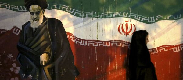 veiled Iranian woman walks past a mural depicting the late revolutionary founder Ayatollah Khomeini, and national Iranian flag, painted on the wall of the former U.S. Embassy, in Tehran, Iran veiled Iranian woman walks past a mural depicting the late revolutionary founder Ayatollah Khomeini, and national Iranian flag, painted on the wall of the former U.S. Embassy, in Tehran, Iran - Sputnik International