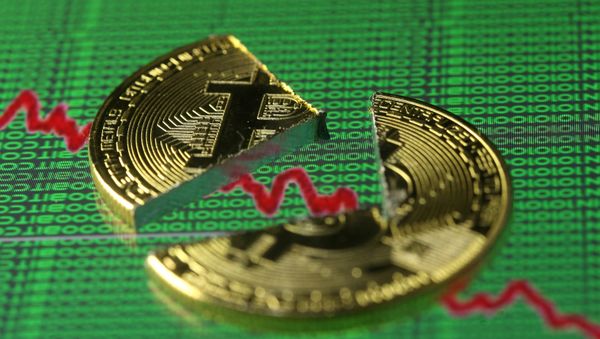 Broken representation of the Bitcoin virtual currency, placed on a monitor that displays stock graph and binary codes, are seen in this illustration picture, December 21, 2017 - Sputnik International