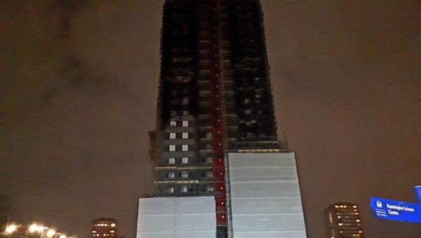 The blackened hulk of Grenfell Tower, which is only partially covered up, in north Kensington - Sputnik International
