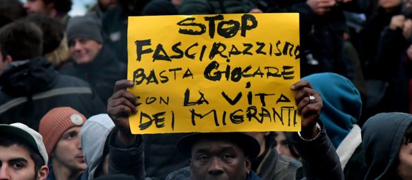 A protester holds a placard reading stop to the fascism and racism, stop playing with the migrants' life during an anti-racism demonstration one week after an attack that injured at least six migrants, on February 10, 2018 in Macerata - Sputnik International