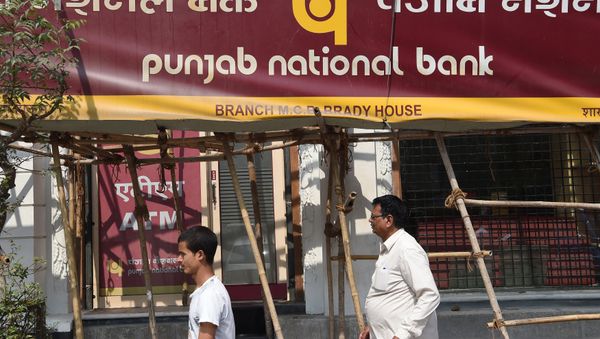 Indian men walk past signage for the state-owned Punjab National Bank (PNB) in Mumbai on February 14, 2018 - Sputnik International