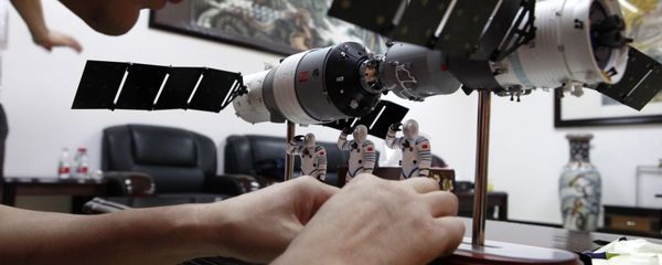 A Chinese official arranges astronaut figures with a scale model of the Shenzhou 9 module docking with China's Tiangong 1 space module to present them at a press conference at the Jiuquan satellite launch center near Jiuquan in western China's Gansu province, Friday, June 15, 2012 - Sputnik International