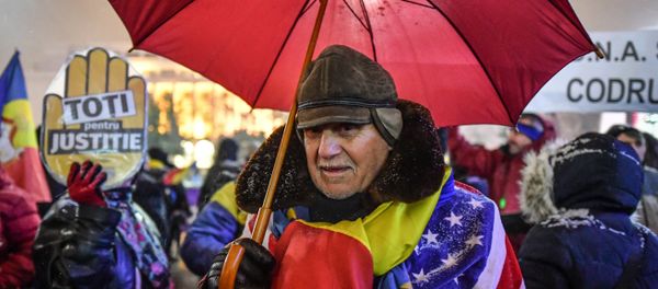 A man wear Romanian and US flags during a protest against the Justice minister and the corruption in front of the Romanian Government in Bucharest A man wear Romanian and US flags during a protest against the Justice minister and the corruption in front of the Romanian Government in Bucharest - Sputnik International