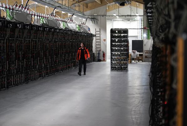 In this photo taken on Jan. 17, 2018, a worker walks along a row of computer rigs that run around the clock 'mining' bitcoin inside the Genesis Mining cryptocurrency mine in Keflavik, Iceland - Sputnik International