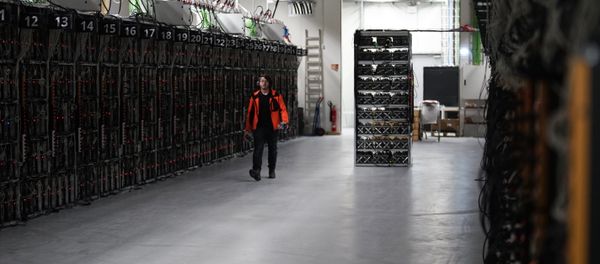 In this photo taken on Jan. 17, 2018, a worker walks along a row of computer rigs that run around the clock 'mining' bitcoin inside the Genesis Mining cryptocurrency mine in Keflavik, Iceland In this photo taken on Jan. 17, 2018, a worker walks along a row of computer rigs that run around the clock 'mining' bitcoin inside the Genesis Mining cryptocurrency mine in Keflavik, Iceland - Sputnik International