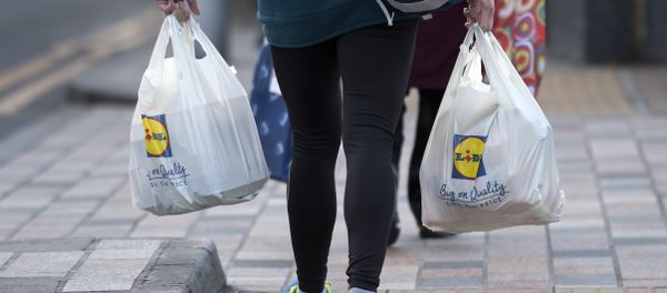 A person leaves with their goods in plastic carrier bags after shopping at a branch of Lidl in south London on January 10, 2018 - Sputnik International