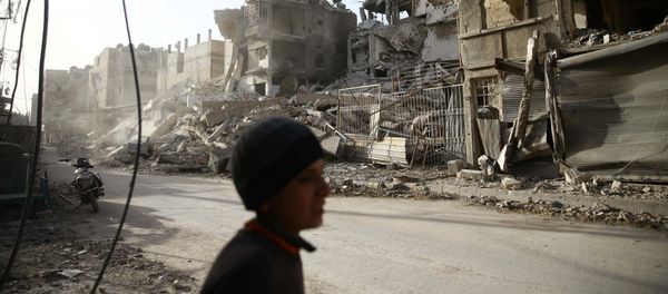 A boy walks near damaged buildings in the besieged town of Douma in eastern Ghouta in Damascus, Syria, March 1, 2018 - Sputnik International