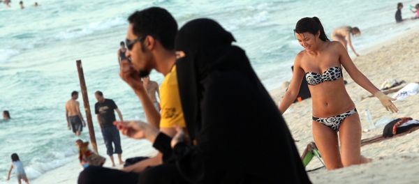A foreign woman sunbathes near an Emirati couple on a beach in Dubai (File) - Sputnik International