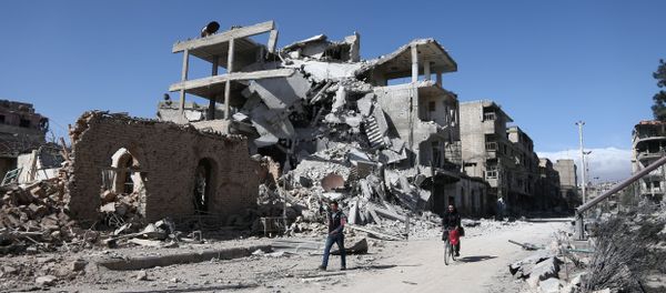 Syrians walk past destroyed buildings in the rebel-held town of Hamouria, in the besieged Eastern Ghouta region on the outskirts of the capital Damascus, on March 9, 2018 Syrians walk past destroyed buildings in the rebel-held town of Hamouria, in the besieged Eastern Ghouta region on the outskirts of the capital Damascus, on March 9, 2018 - Sputnik International