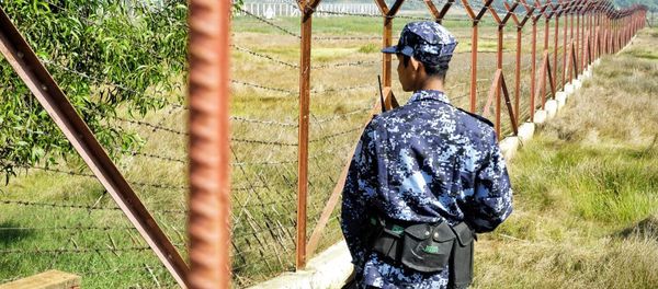 A Myanmar border guard stands next to fencing in a field on the outskirts of Maungdaw in Rakhine state on January 24, 2018 - Sputnik International