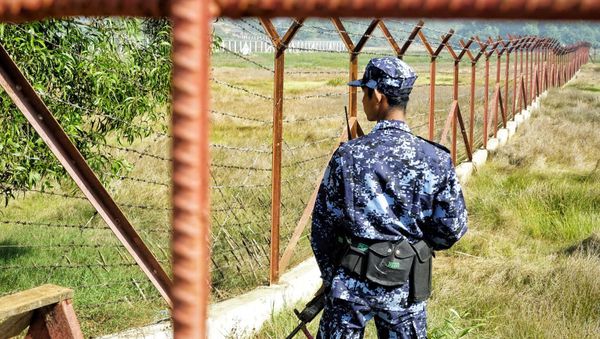 A Myanmar border guard stands next to fencing in a field on the outskirts of Maungdaw in Rakhine state on January 24, 2018 - Sputnik International