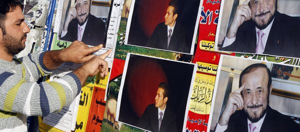 A member of the Alawite community pastes on a wall, in the northern Lebanese city of Tripoli 06 December 2007, pictures of Syrian opposition leader Rifaat al-Assad (R) and his son Ribal - Sputnik International