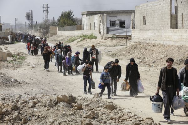 Syrians civilians evacuated from the Eastern Ghouta enclave pass with belongings through the regime-controlled corridor opened by government forces in Hawsh al-Ashaari, east of the enclave town of Hamouria on the outskirts of the capital Damascus on March 15, 2018 - Sputnik International