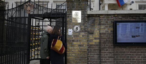 Two people wait to get into the Russian Embassy as a man works to untangle the national flag flown from the Russian Embassy, after it became entangled on its staff at the embassy in London, Wednesday, March 14, 2018 Two people wait to get into the Russian Embassy as a man works to untangle the national flag flown from the Russian Embassy, after it became entangled on its staff at the embassy in London, Wednesday, March 14, 2018 - Sputnik International