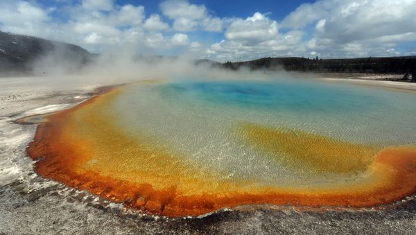 View of the 'Sunset Lake' hot spring with it's unique colors caused by brown, orange and yellow algae-like bacteria called Thermophiles, that thrive in the cooling water turning the vivid aqua-blues to a murkier greenish brown, in the Yellowstone National Park, Wyoming on June 1, 2011 - Sputnik International