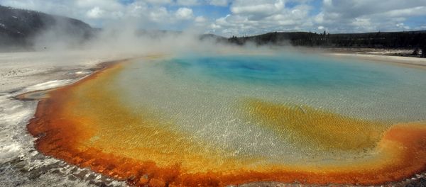 View of the 'Sunset Lake' hot spring with it's unique colors caused by brown, orange and yellow algae-like bacteria called Thermophiles, that thrive in the cooling water turning the vivid aqua-blues to a murkier greenish brown, in the Yellowstone National Park, Wyoming on June 1, 2011 - Sputnik International